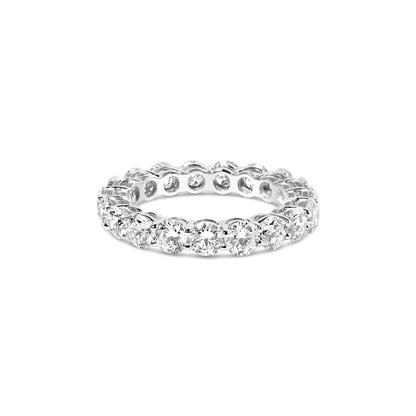 White metal eternity ring with round white gemstones in prong settings viewed from a front angle on a white background.