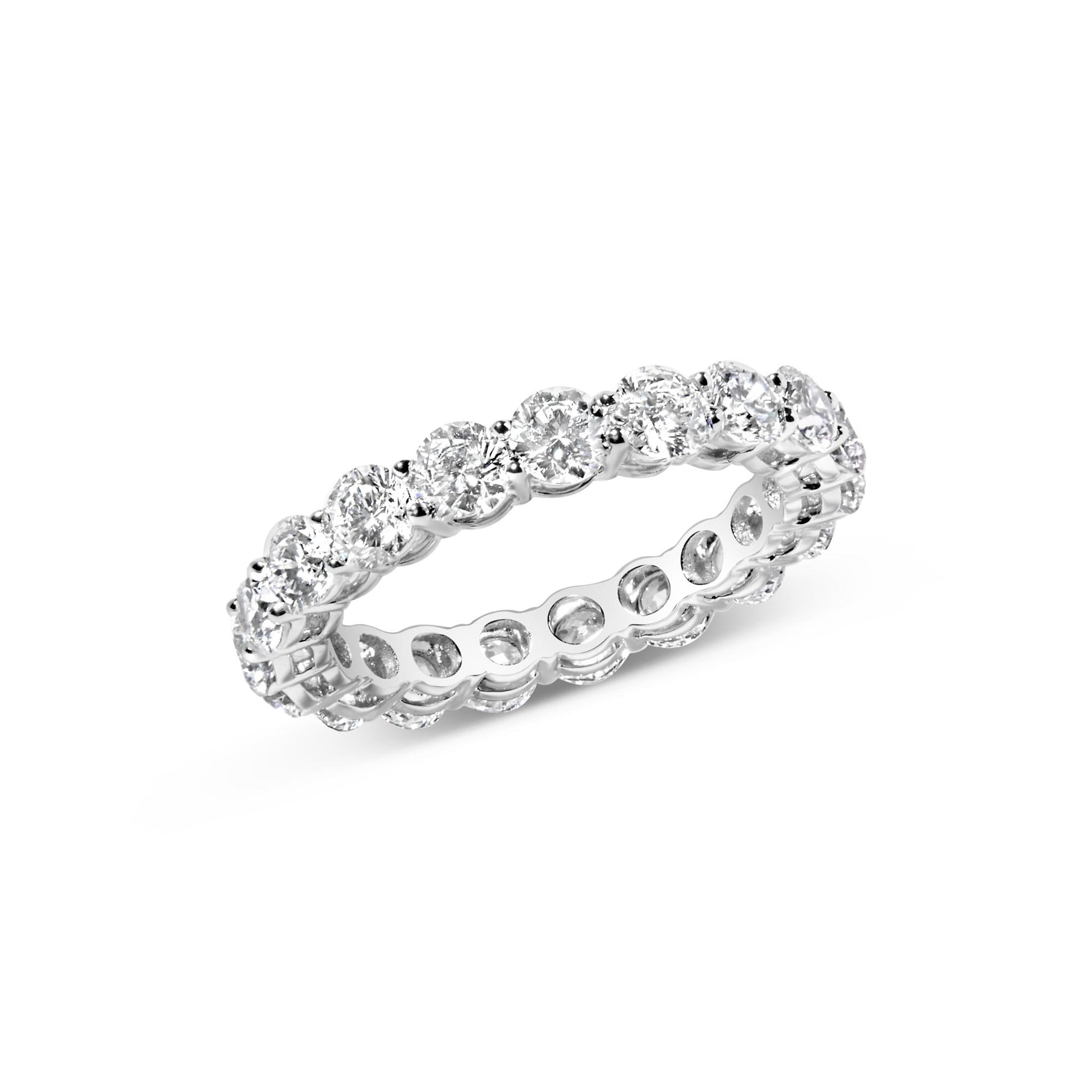 White metal eternity ring with round white gemstones in prong settings, shown at an angle.