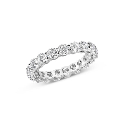 White metal eternity ring with round white gemstones in prong settings, shown at an angle.