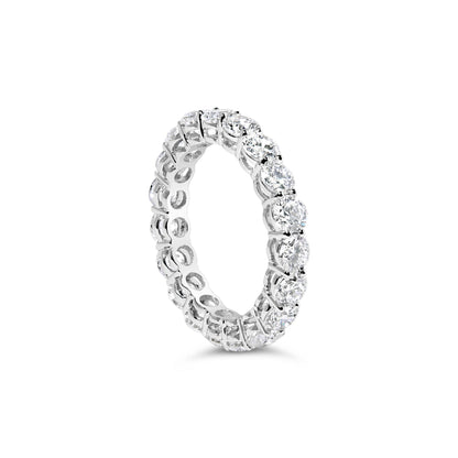 White metal eternity ring with round white gemstones in prong settings, shown from a slightly angled side view.
