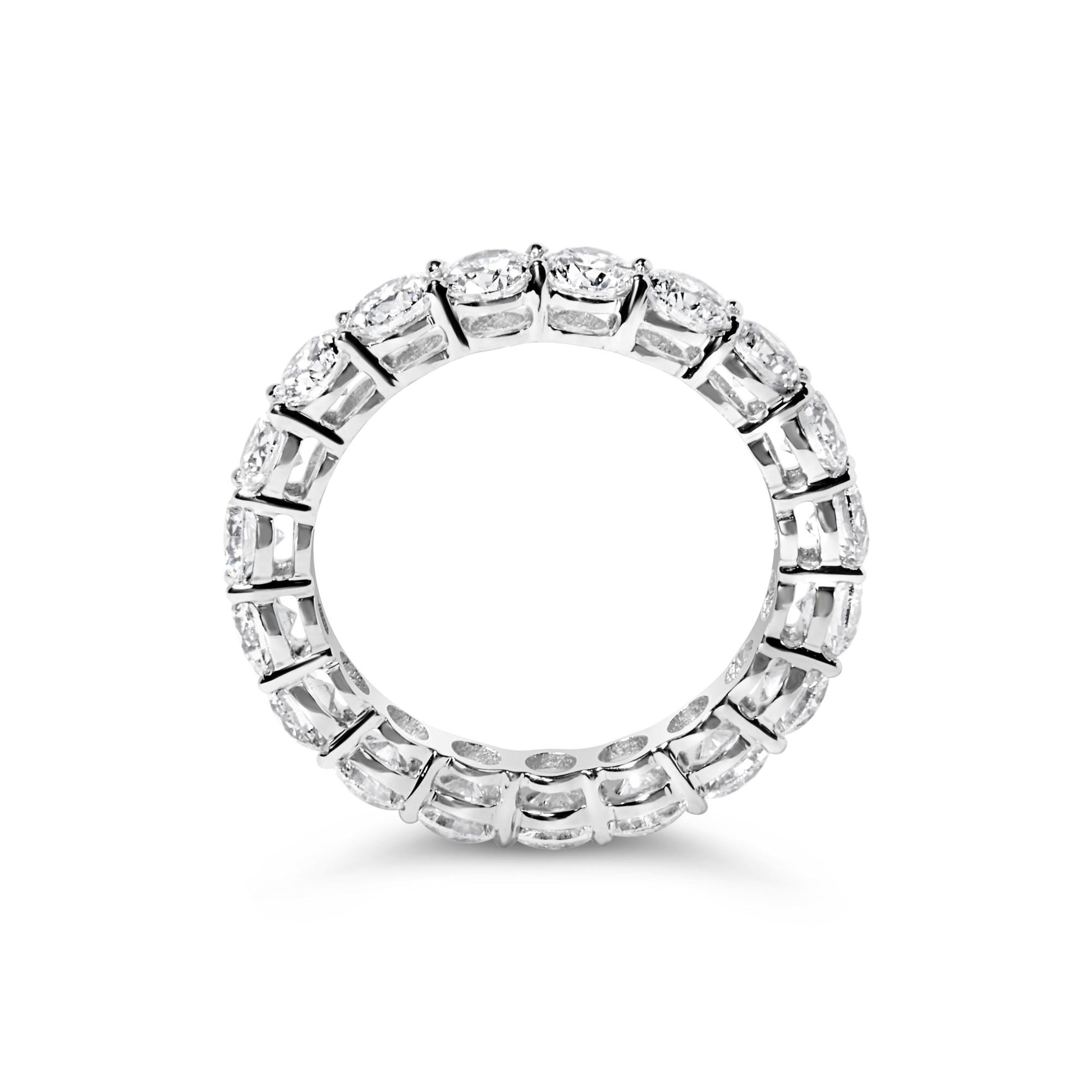 Top-down view of a white ring with round white gemstones set in prong settings encircling the band.