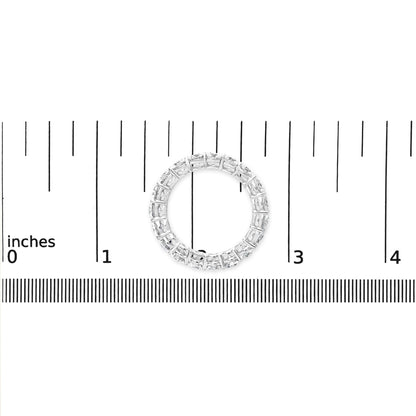 Top view of a white metal ring with round white gemstones in prong settings, placed on a ruler for size reference.