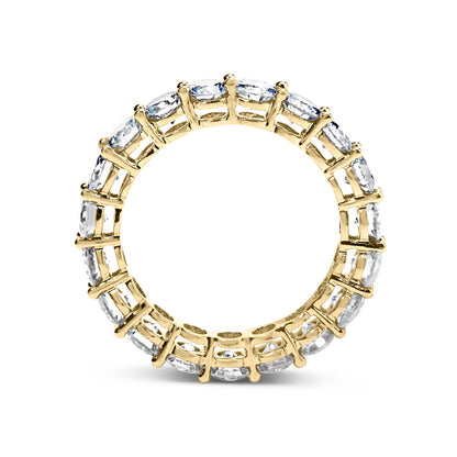 Top-down view of a yellow ring with round white gemstones set in a shared prong setting encircling the entire band.