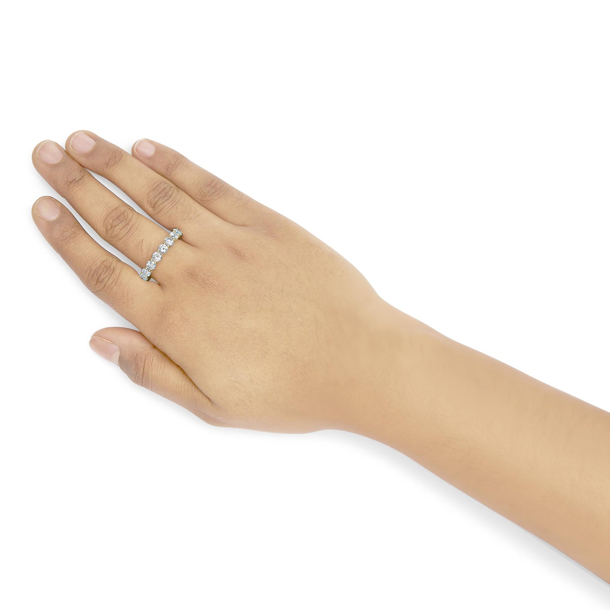 Close-up front angle of a yellow metal ring with round white gemstones in shared prong settings, worn on a model's finger.