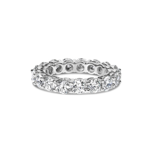 White metal ring viewed from front angle, featuring round white gemstones in shared prong setting encircling the band.