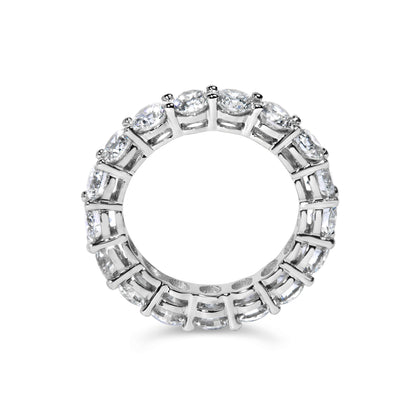 Top-down view of a white metal ring set with round white gemstones in a shared prong setting encircling the band.