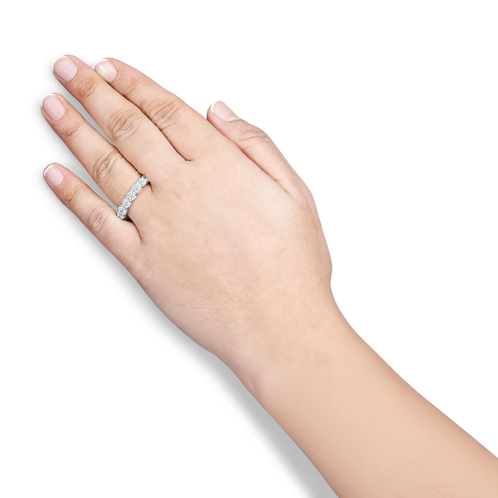 White metal ring with round white gemstones in shared prong setting worn on a model's finger, shot from above.