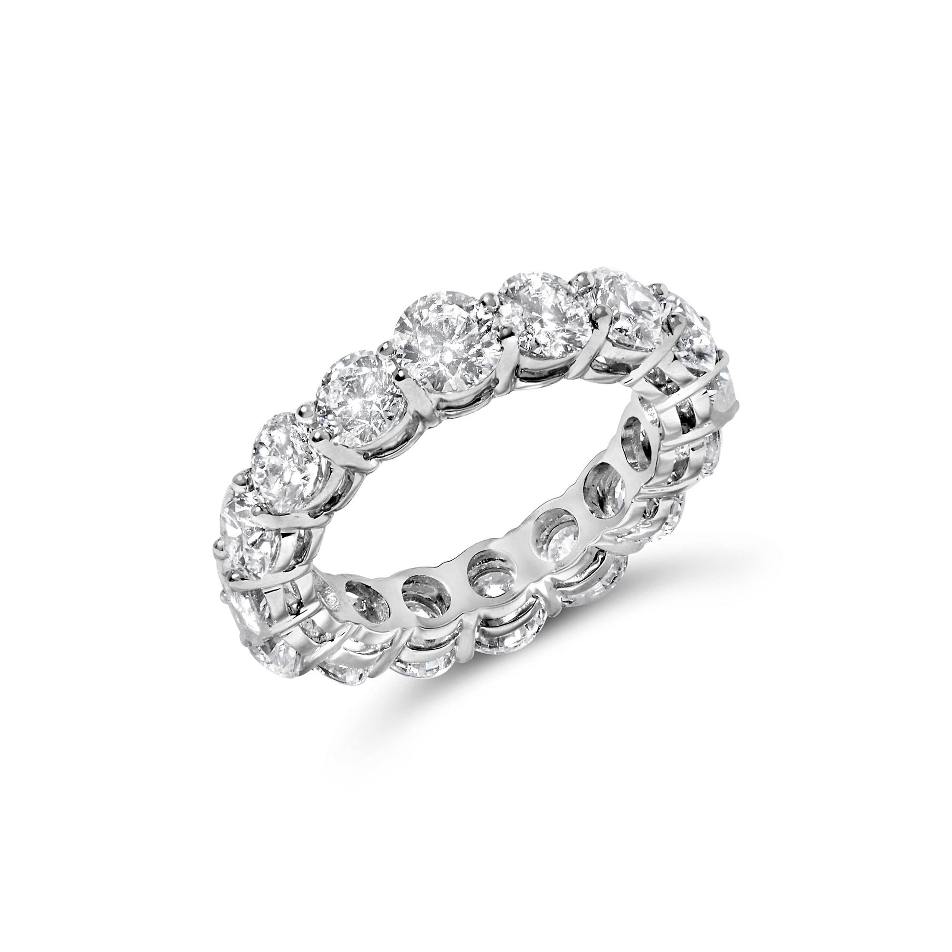 White metal eternity ring with round white gemstones in prong settings, shown at an angled close-up.
