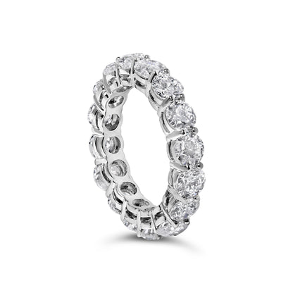 White metal eternity ring with round white gemstones in prong settings, shown at an angled close-up.