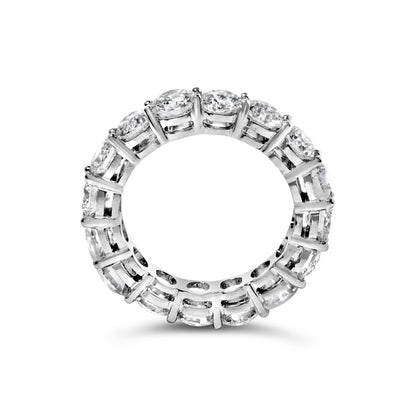 Top-down view of a white metal eternity ring with round white gemstones in prong settings encircling the entire band.