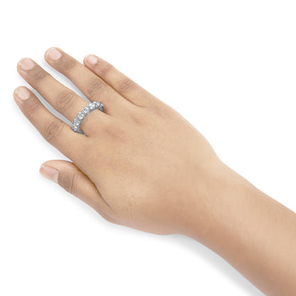 White metal ring with round white gemstones in prong setting, worn on a model's hand, shot from above at a slight angle.