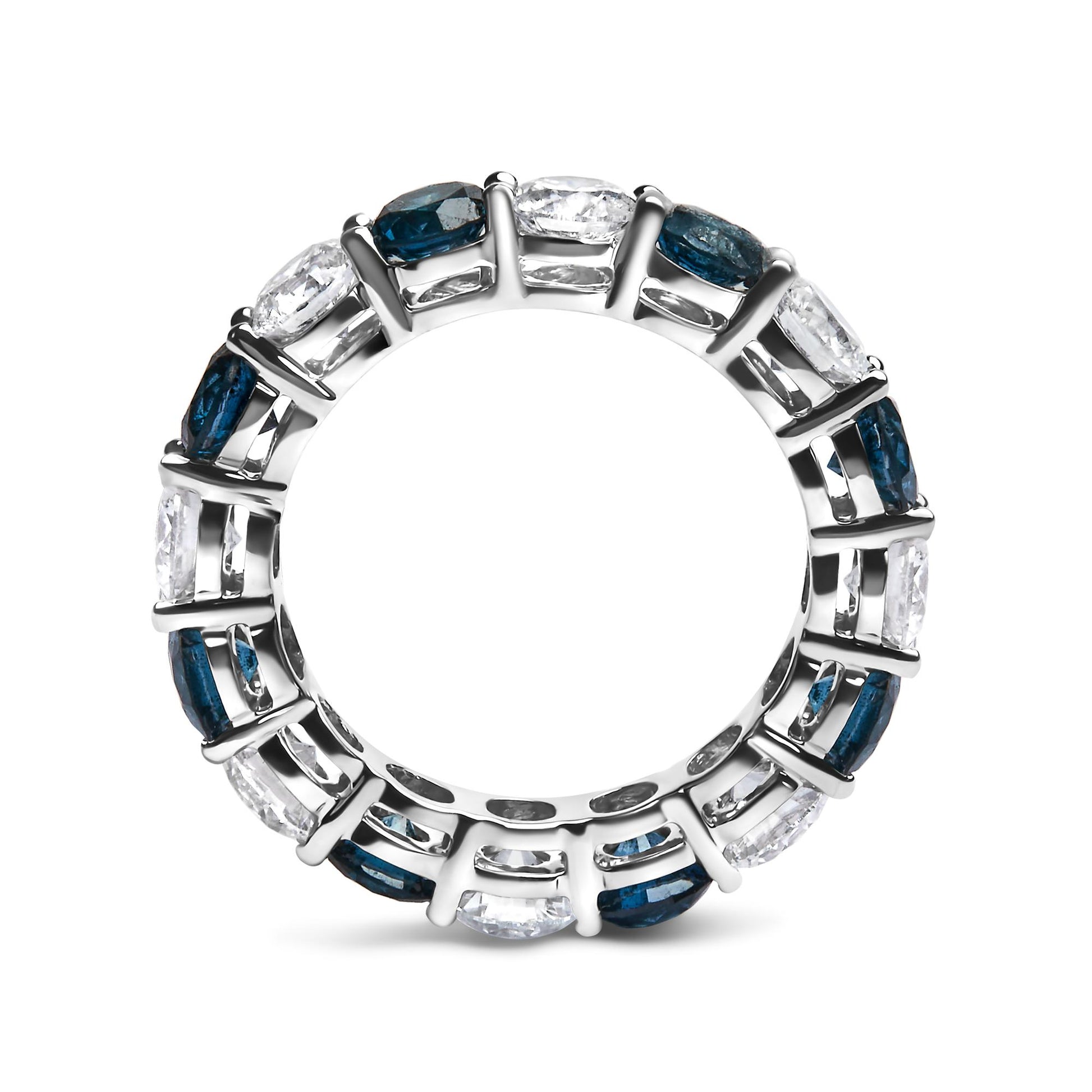 Top-down close-up of a white metal ring with alternating round blue and white gemstones set in shared prong settings, shown against a white background.