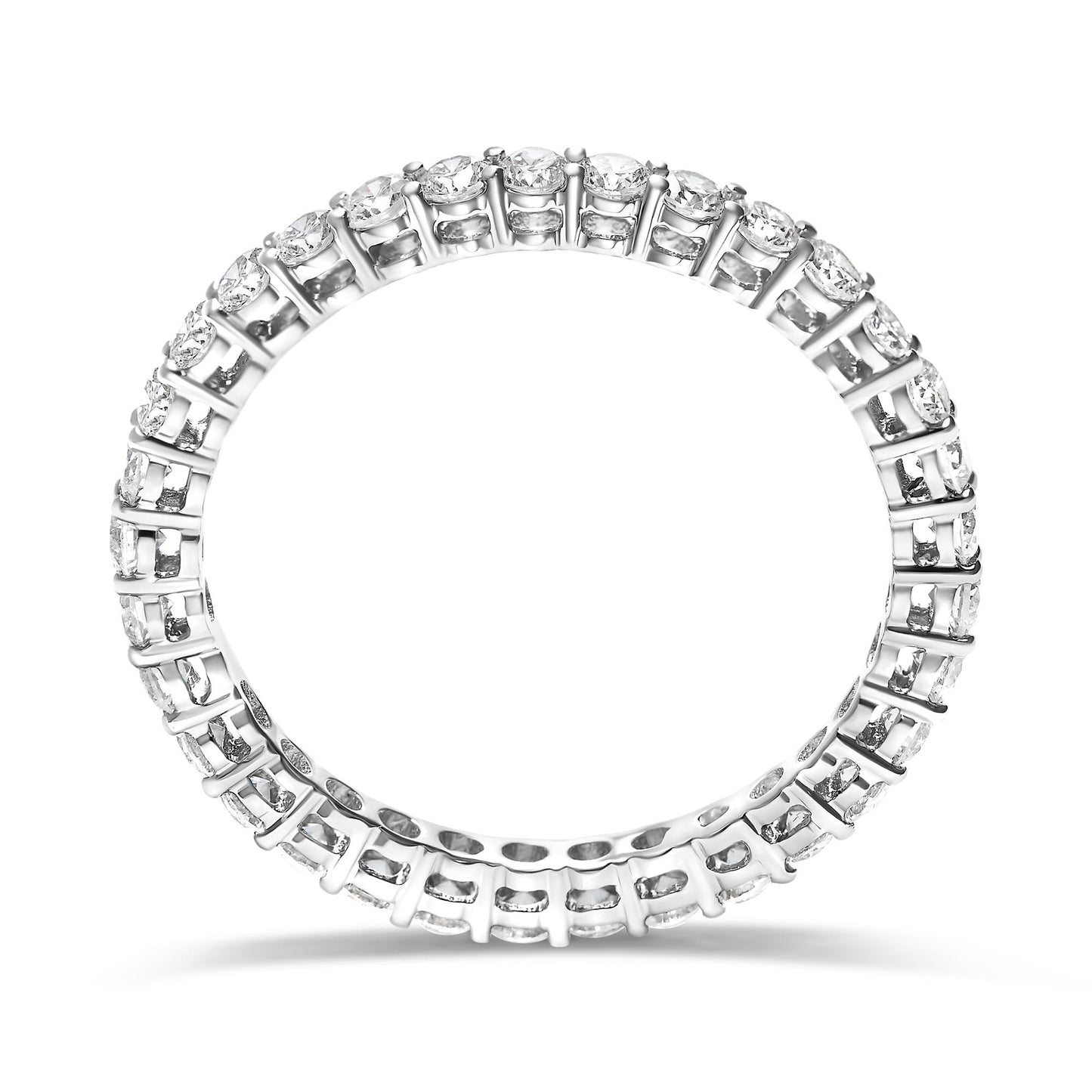Top-down angled view of a white metal ring featuring round white gemstones set in shared prong settings encircling the entire band.