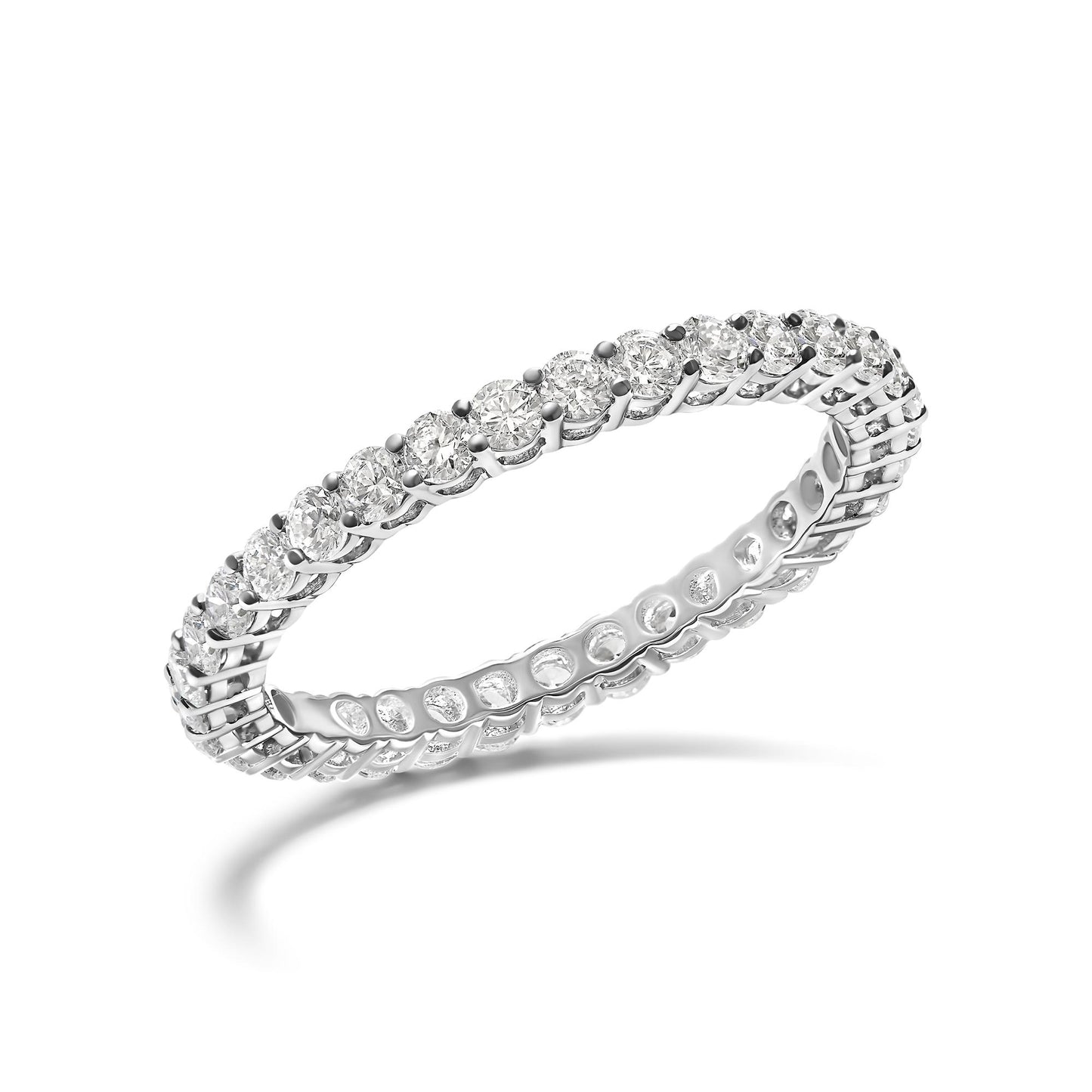 White metal eternity ring with round white gemstones in shared prong setting, angled view.