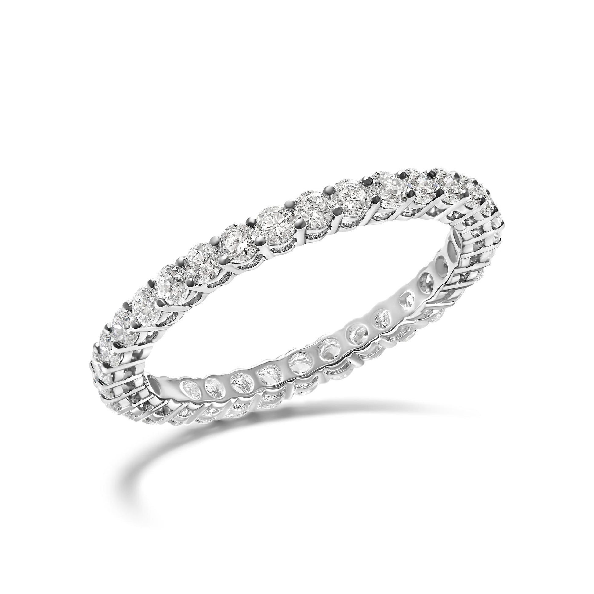 White metal eternity ring with round white gemstones in shared prong setting, angled view.