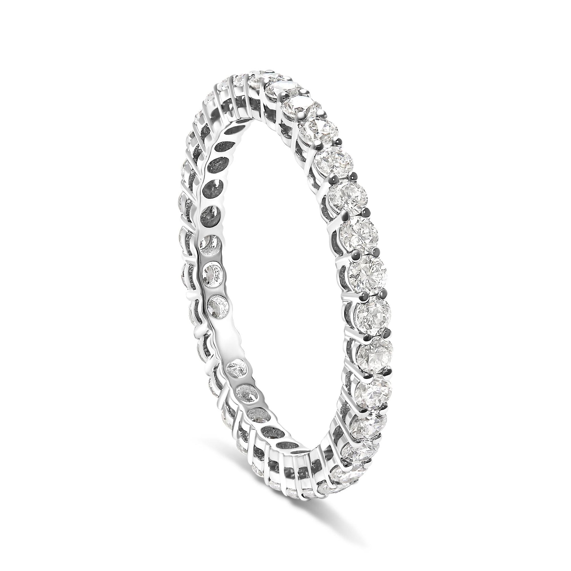 White metal ring with round white gemstones in shared prong setting, shown at a slight angle against a white background.