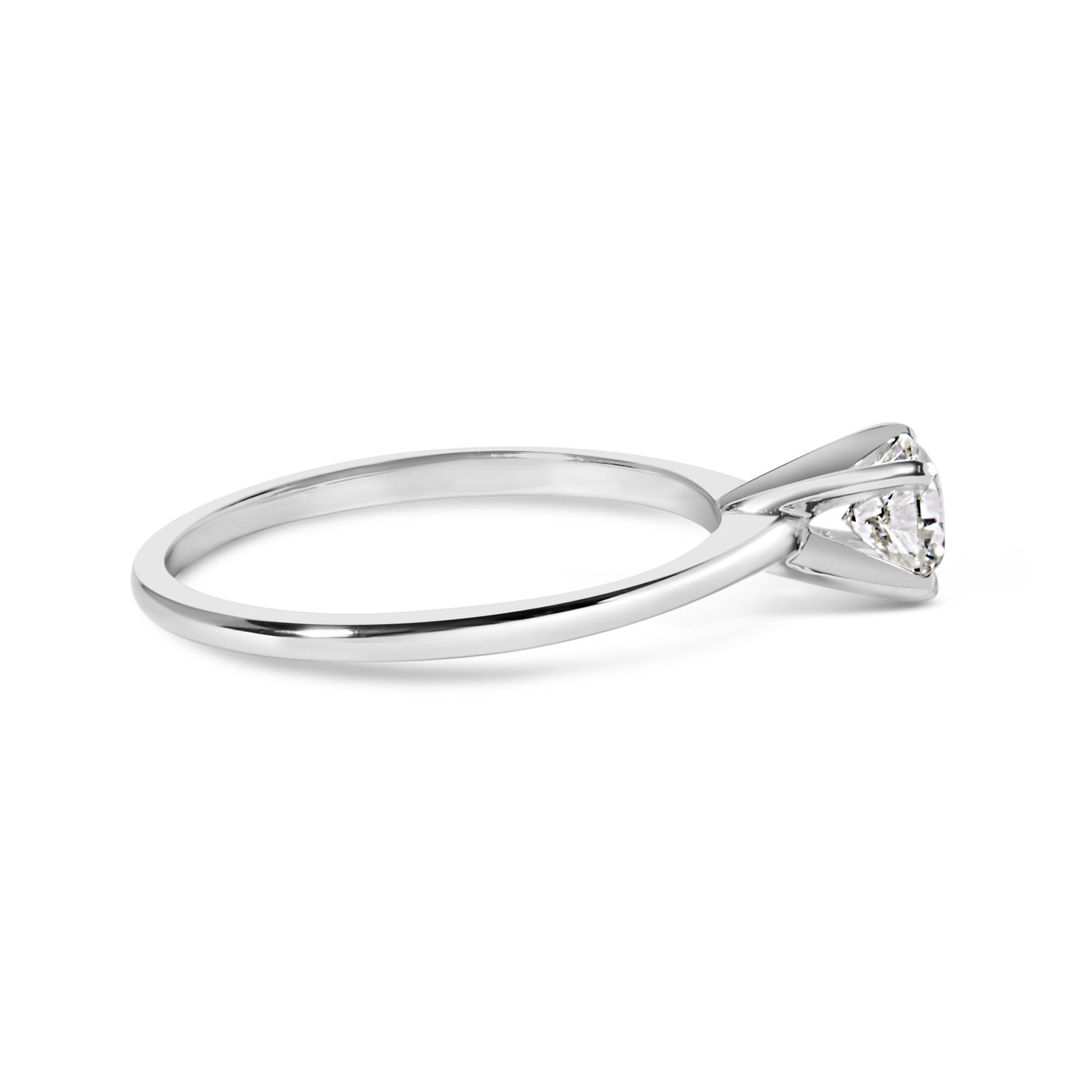Side angle view of a white metal ring with a single round white gemstone in a four-prong setting.