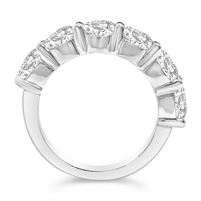 Close-up side view of a white ring featuring six round white gemstones set in a shared prong setting along the top half of the band.
