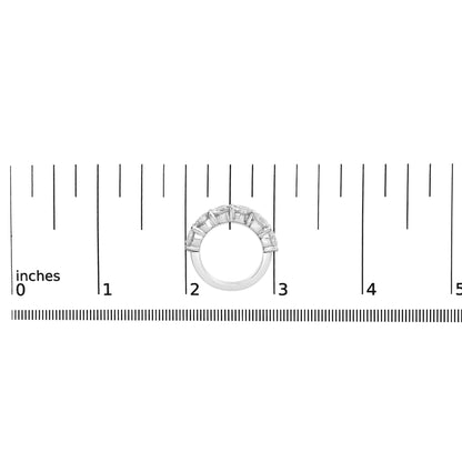 White metal ring with six round white gemstones in shared prong setting, shown resting flat on a ruler scale, top-down view.