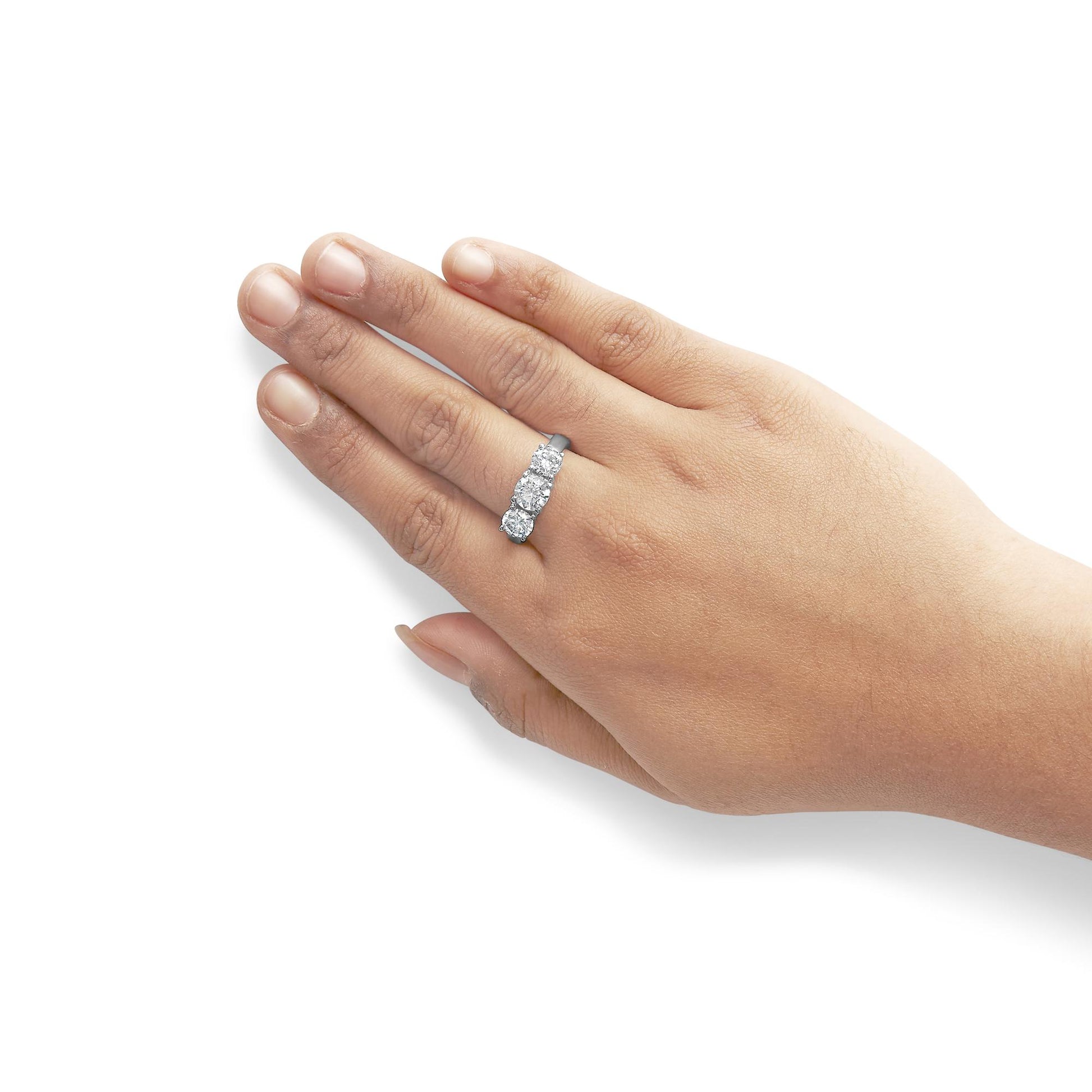 White metal ring with three white round gemstones in prong settings, worn on a model's hand, shown from above at an angle.