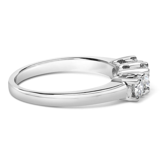 Side angle view of a white metal ring featuring three round white gemstones set in 4-prong settings.