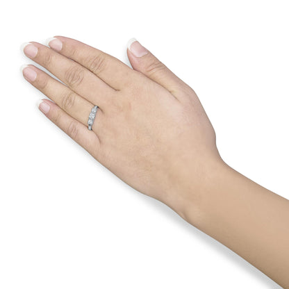 White metal ring with three round white gemstones in 4-prong settings, worn on a model’s left hand, angled top-down.