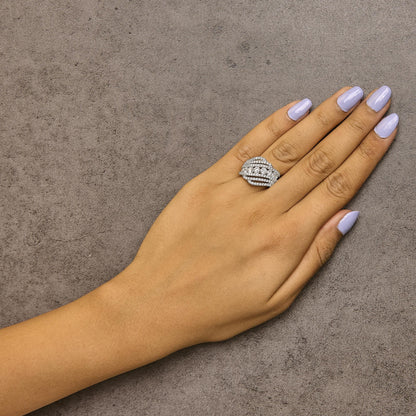 White metal ring with multiple rows of round white gemstones in prong settings, shown worn on a model's hand from a top angle.