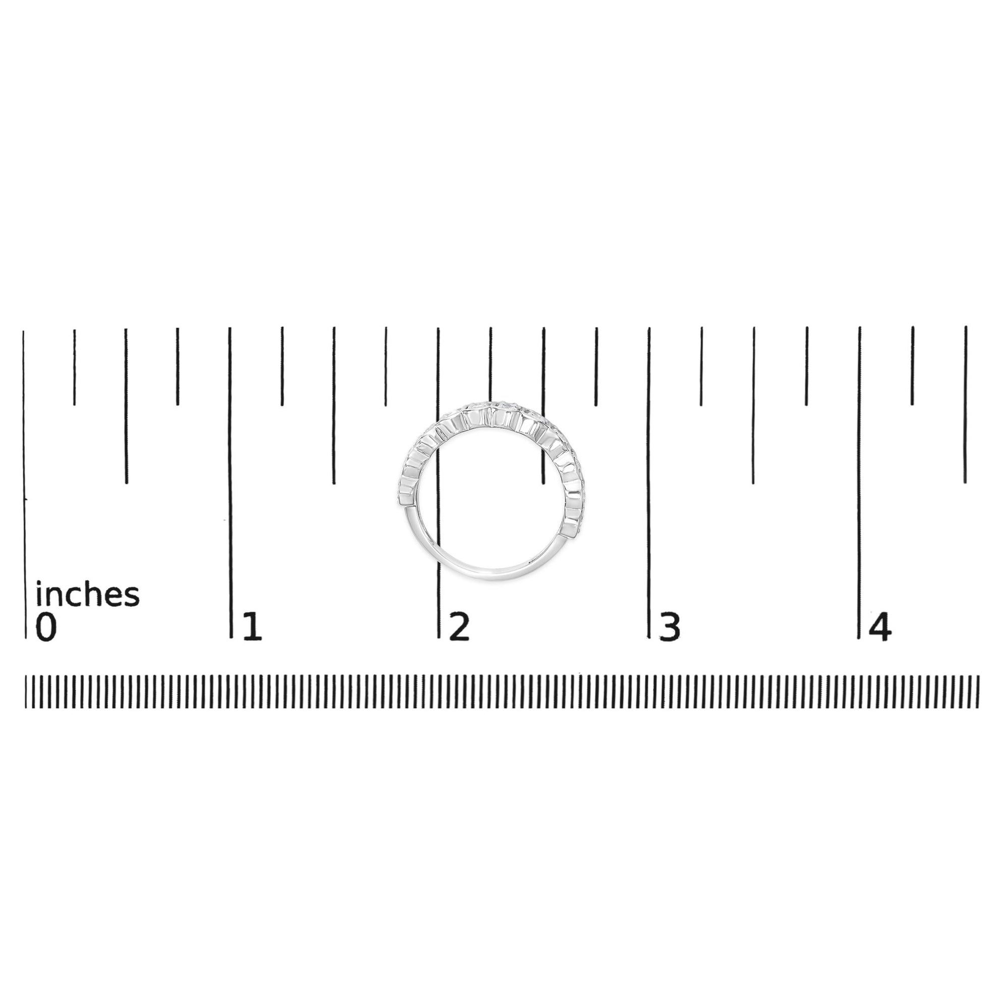 Top-down view of a white ring set with multiple round white gemstones in prong settings, shown on a measurement scale.