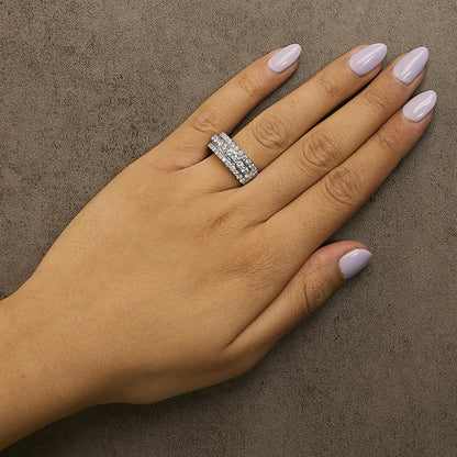 White metal ring with multiple rows of round white gemstones in prong settings, shown worn on a model's hand from a top-down angle.