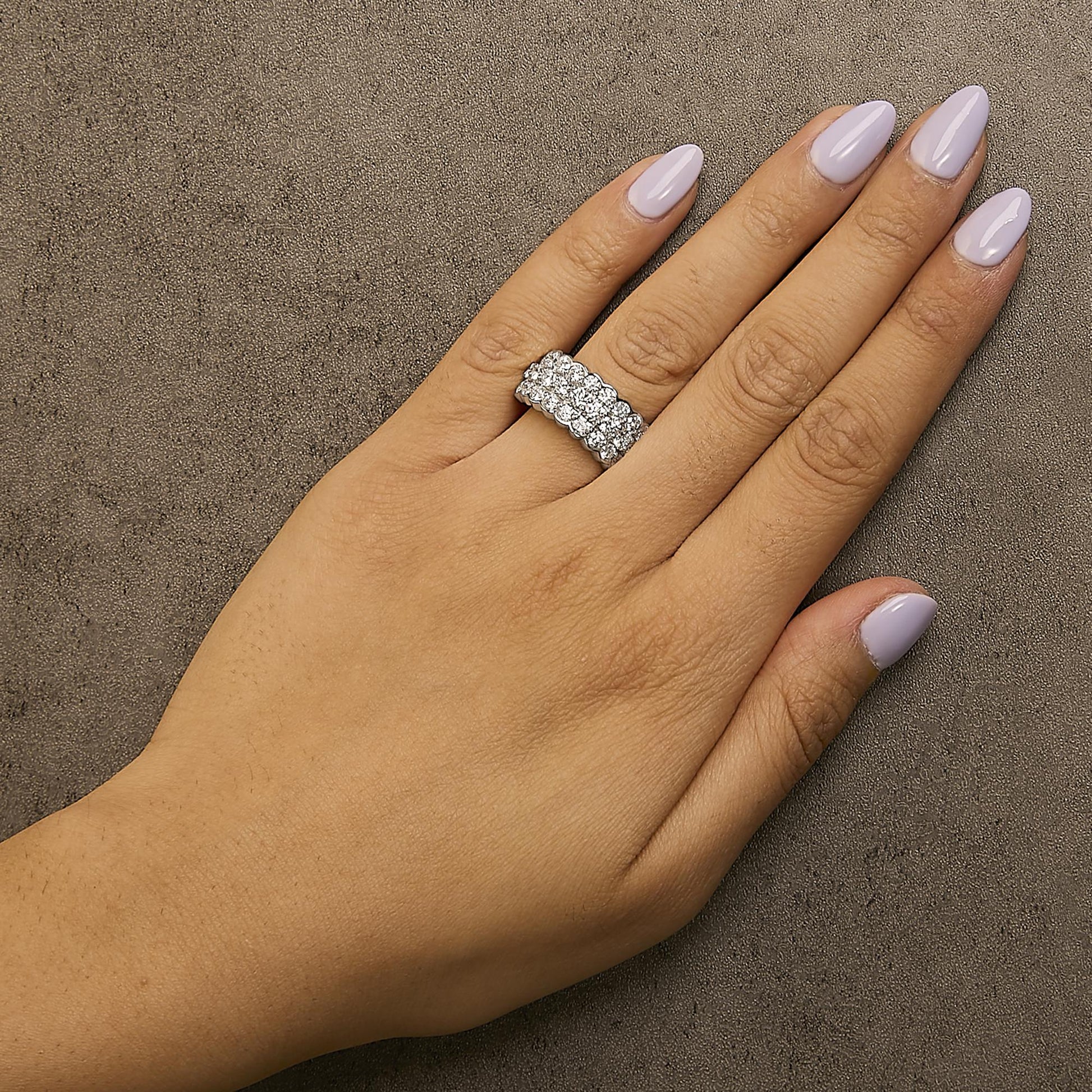 White metal ring with two rows of white round gemstones in prong settings, shown worn on a model's finger, top-down angle.