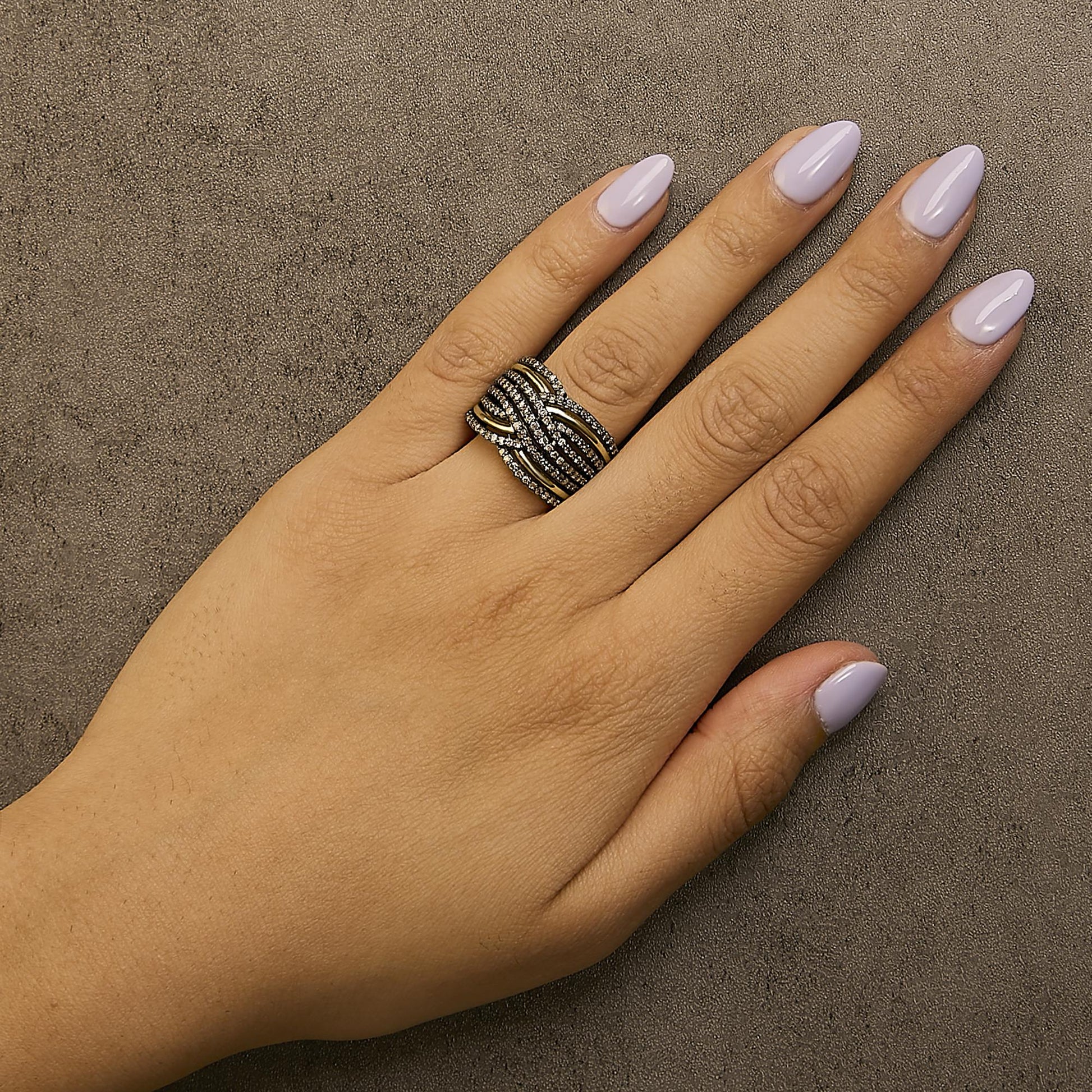 Yellow metal ring with multiple intertwined bands, each set with prong-set round champagne-colored gemstones, shown worn on a model's hand from above.