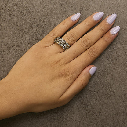 Yellow metal ring with round prong-set champagne-colored gemstones arranged in a crisscross pattern, shown worn on a model's hand from a top angle.