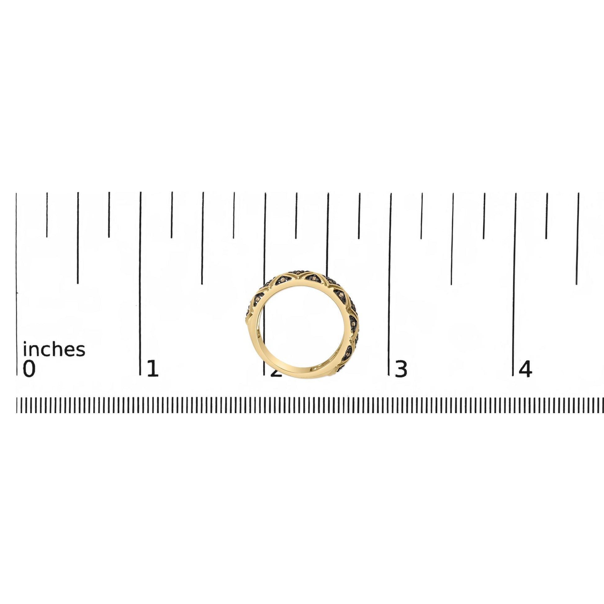 Yellow metal ring with round champagne-colored gemstones in prong settings, shown on a ruler scale from a top-down angle.