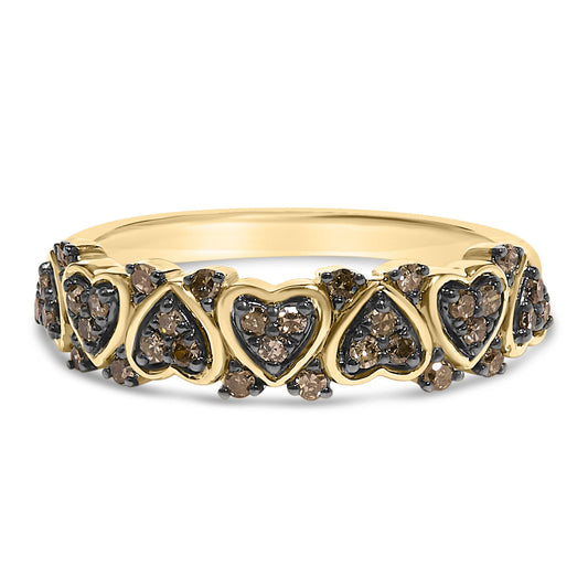Front-facing shot of a yellow metal ring featuring alternating heart and teardrop shapes, each set with round champagne-colored gemstones in prong settings.