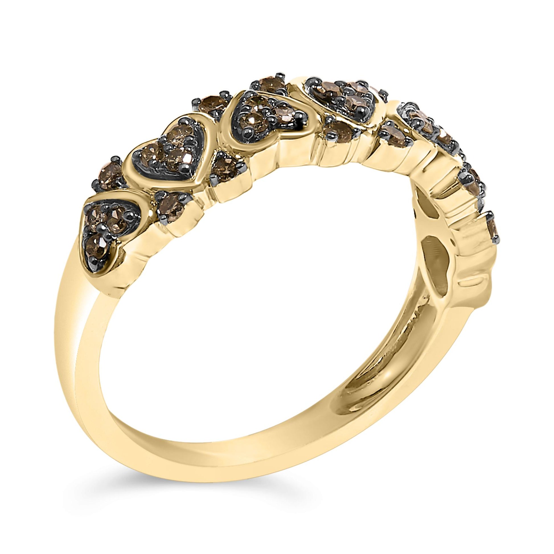 Yellow metal ring with heart-shaped designs, each featuring multiple prong-set round champagne-colored gemstones, shown at an angled close-up view.