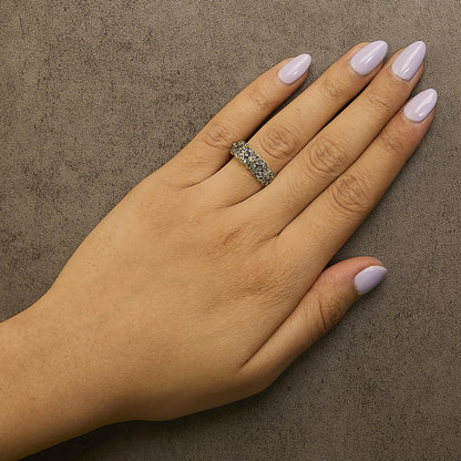 Yellow ring with clusters of round champagne-colored gemstones in prong settings, shown worn on a model's hand from a top-down angle.