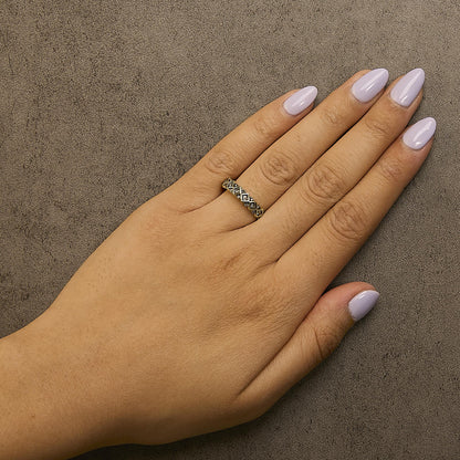 Close-up angled view of a yellow metal ring with multiple round champagne-colored gemstones in prong settings, worn on a model's finger with light purple nail polish.