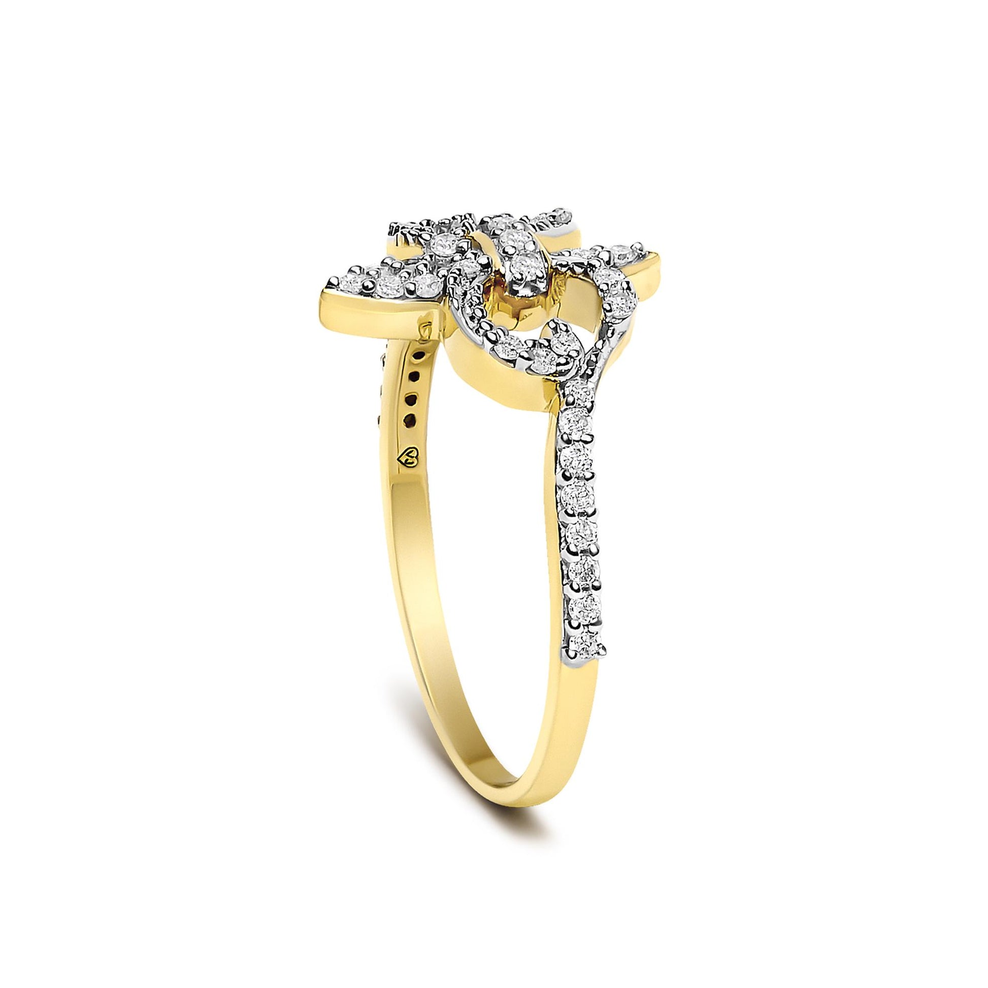 Close-up front angle of a yellow metal ring adorned with numerous round white gemstones set in prong settings along a floral-shaped design.