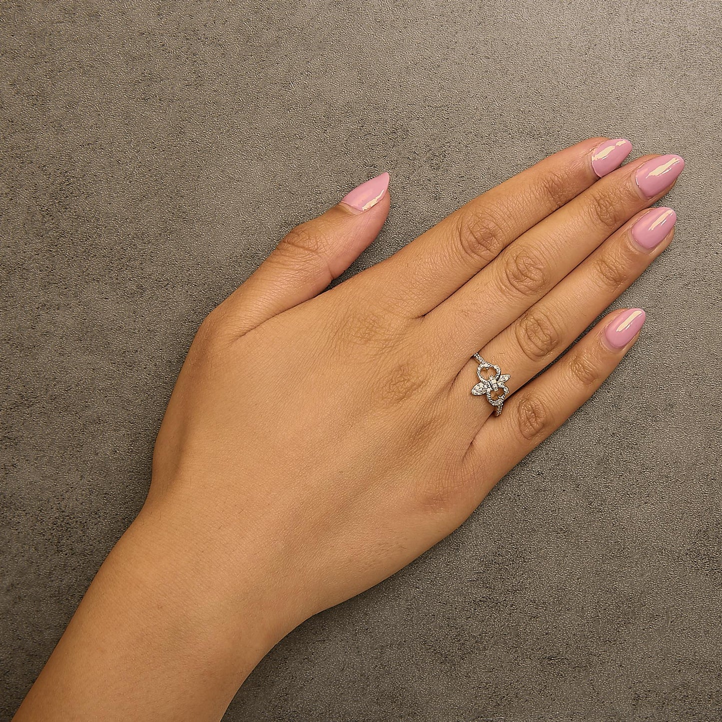 Yellow metal ring with round white gemstones in prong setting, shown worn on a model's finger from a top angle.