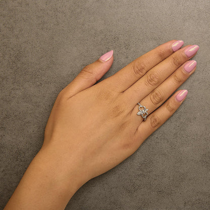 Yellow metal ring with round white gemstones in prong setting, shown worn on a model's finger from a top angle.