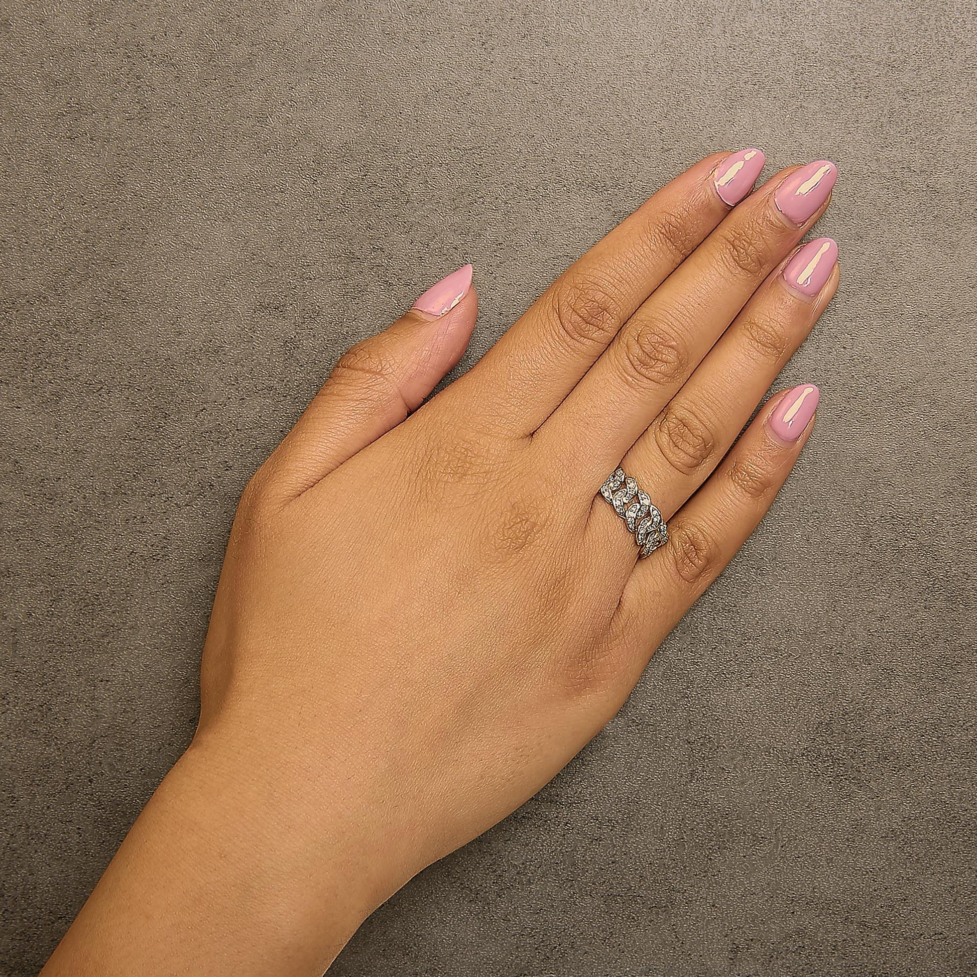 Yellow metal ring with round white gemstones in prong settings arranged in a linked chain pattern, shown worn on a model's finger, angled from above.
