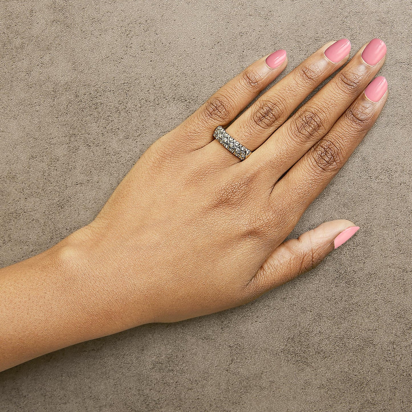 Yellow ring with round, champagne-colored gemstones in prong settings arranged in a crisscross pattern, shown worn on a model's finger with a top-down angle.