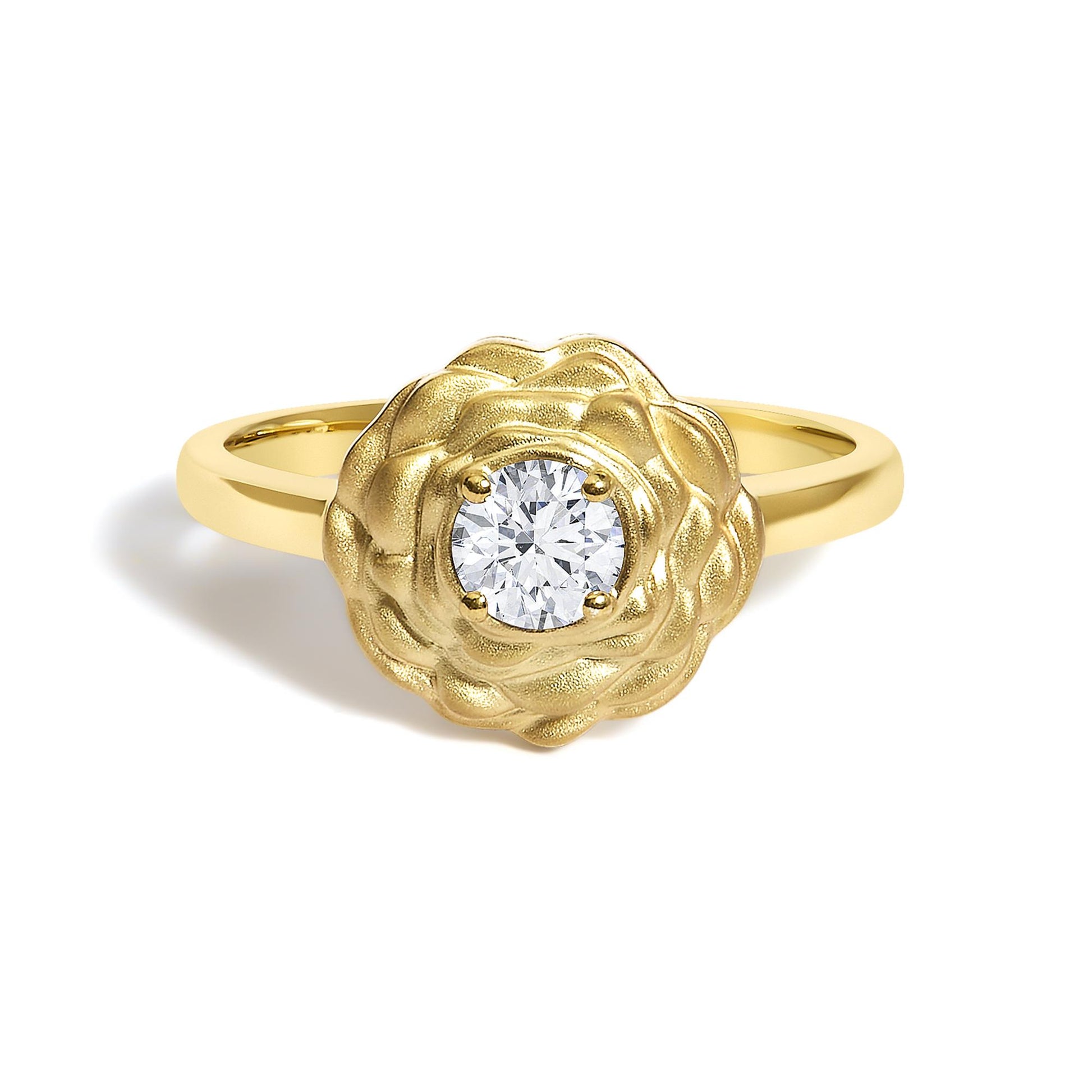 Close-up front angle of a yellow metal ring with a flower-shaped design surrounding a round white gemstone in a four-prong setting.