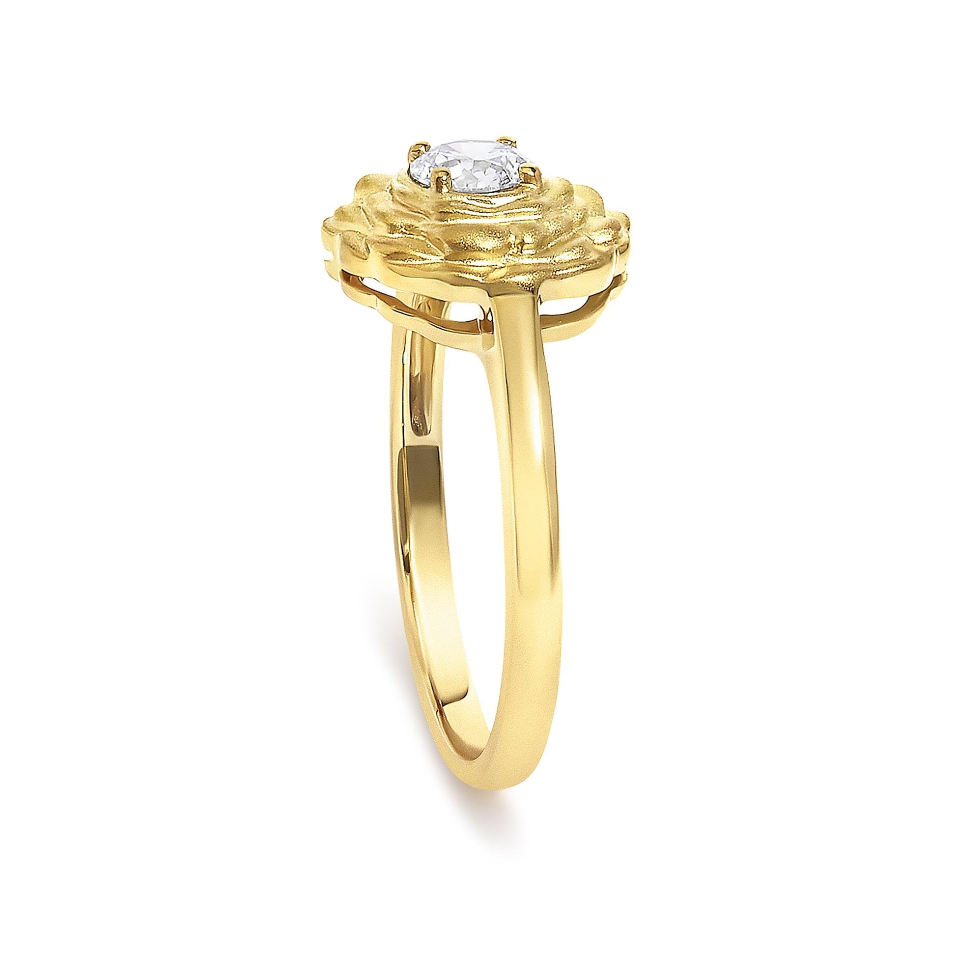 Close-up front angle of a yellow metal ring with a single round white gemstone in a four-prong setting and textured design around the stone.