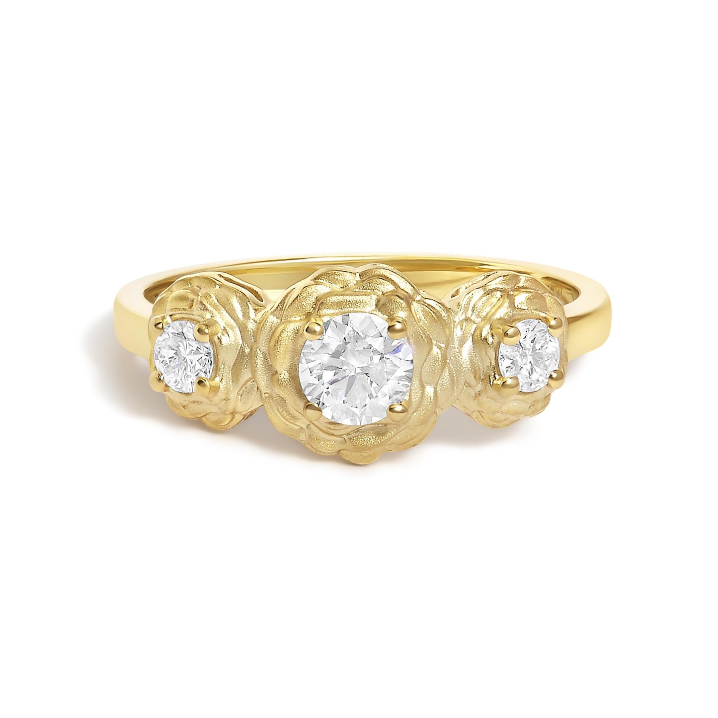 Close-up image of a yellow metal ring with three round white gemstones set in prongs, the center gemstone is larger, surrounded by a textured floral design, shown from the front angle.