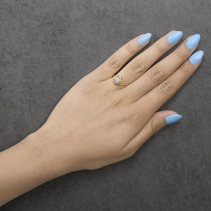 Yellow ring with a round white gemstone in a prong setting, shown worn on a model's hand from a top-down angle.