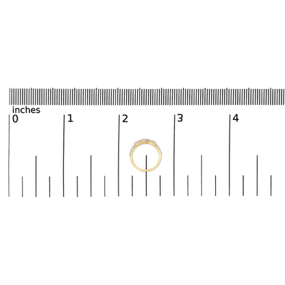 Yellow metal ring with multiple round white gemstones in prong settings along the band, shown on a scale from a top-down angle.