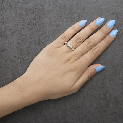 Yellow metal ring with round white gemstones in bezel and prong settings, shown worn on a model's finger, photographed from above at an angle.