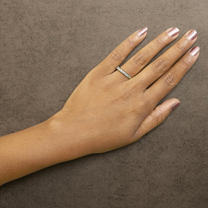 Yellow metal ring with white round gemstones in a micro-pave setting, shown worn on a model's hand from a top angle.