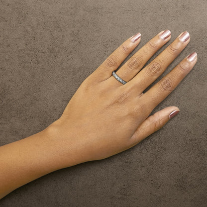 White metal ring with round white gemstones in micro-pave setting, shown on model's hand from top angle.